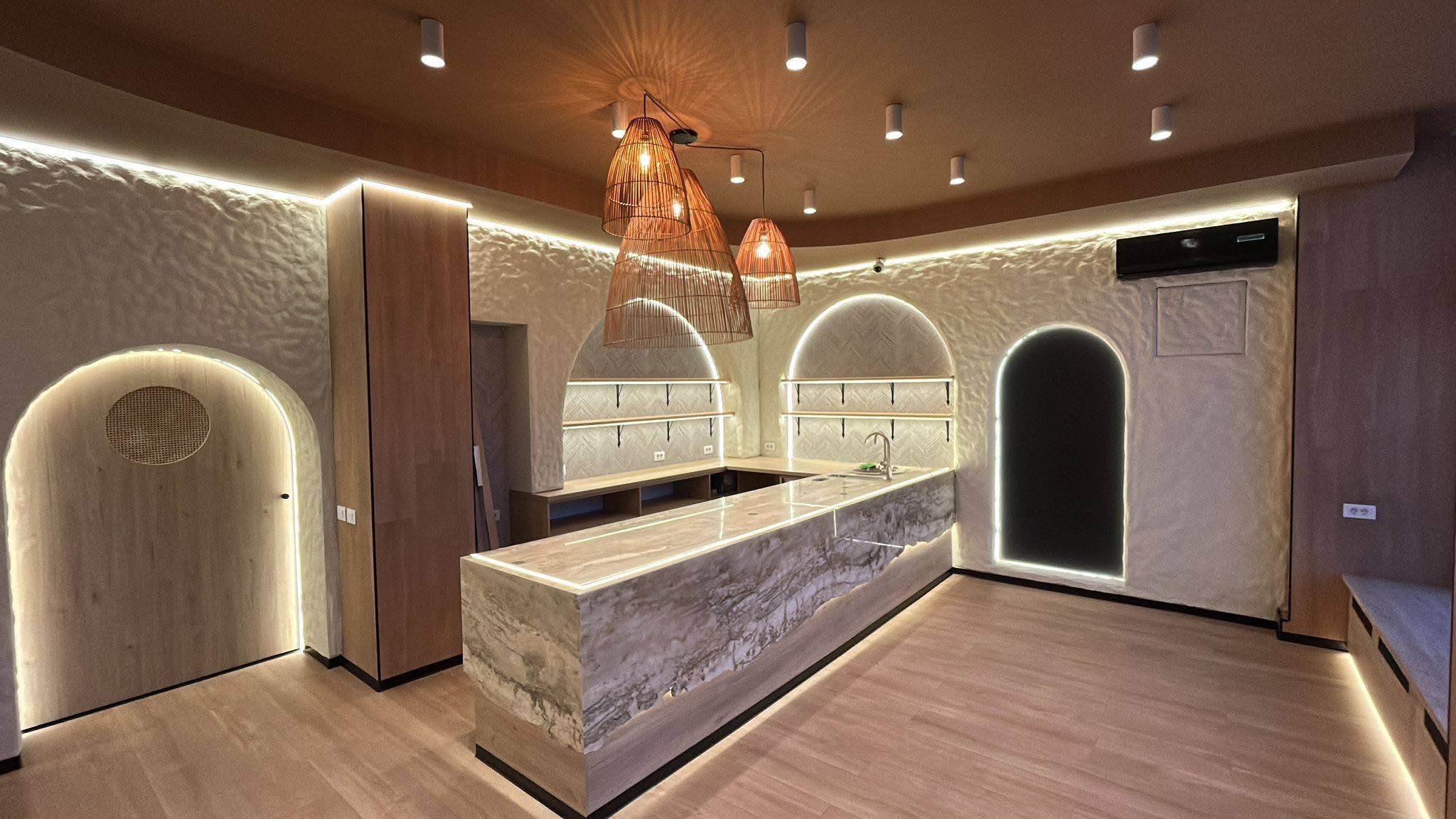 Amenajare interioară HoReCa cu tencuială decorativă, tavan din lambriu și iluminat ambiental pe arcade